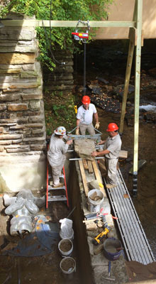 A team of Fallingwater’s preservation maintenance technicians resets large capstones following repairs to the wall of the plunge pool in 2017. A team of Fallingwater’s preservation maintenance technicians resets large capstones following repairs to the wall of the plunge pool in 2017.